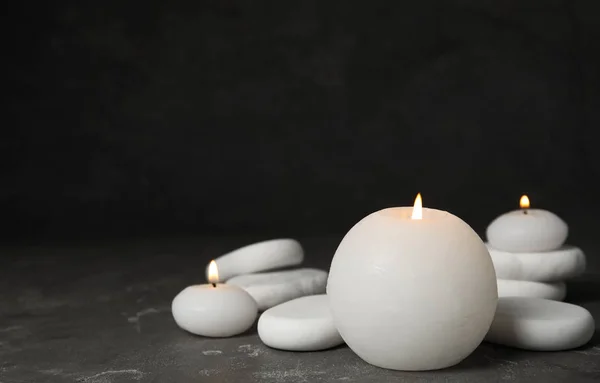 Hořící svíčky a bílé lázeňské kameny na šedém stole, prostor pro text — Stock fotografie