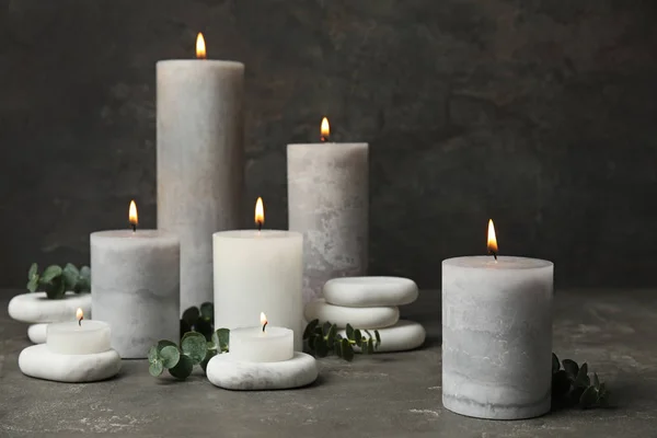 Composition with burning candles, spa stones and eucalyptus on grey table — Stock Photo, Image