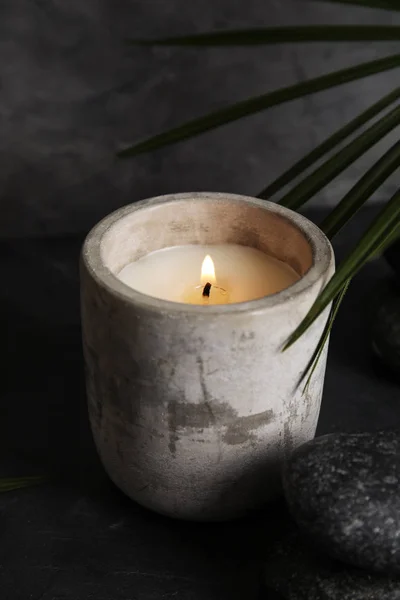 Folha de palma perto de velas acesas e pedras de spa na mesa escura — Fotografia de Stock