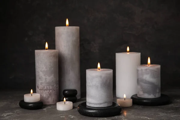 Горящие свечи и черные спа-камни на сером столе — стоковое фото