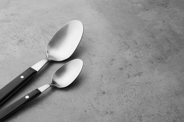 Limpiar cucharas vacías sobre fondo gris, espacio para texto — Foto de Stock