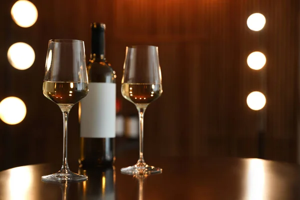 Garrafa e copos de vinho na mesa contra fundo desfocado. Espaço para texto — Fotografia de Stock