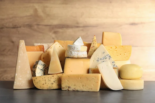 Verschillende soorten heerlijke kaas op tafel tegen houten achtergrond — Stockfoto