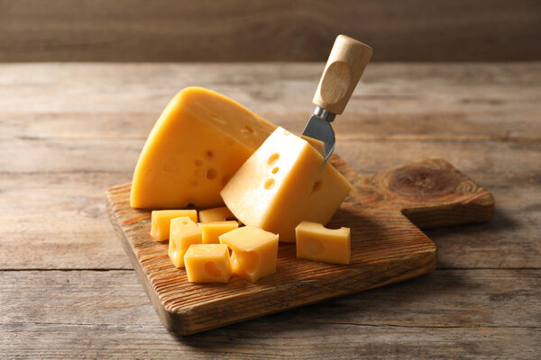 Serving board with delicious cheese on wooden table