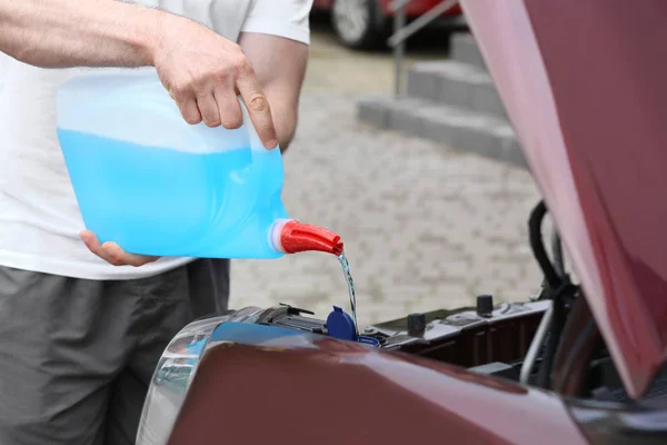 Man hälla vätska från plast kanister i bil spolarvätska reservoar, närbild — Stockfoto