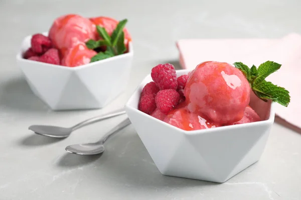 Delicioso helado rosa con frambuesas y menta en cuencos sobre mesa de mármol gris — Foto de Stock