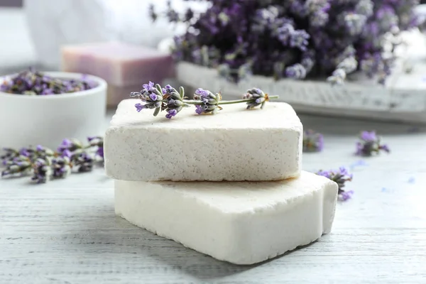 Handmade soap bars with lavender flowers on white wooden table, closeup