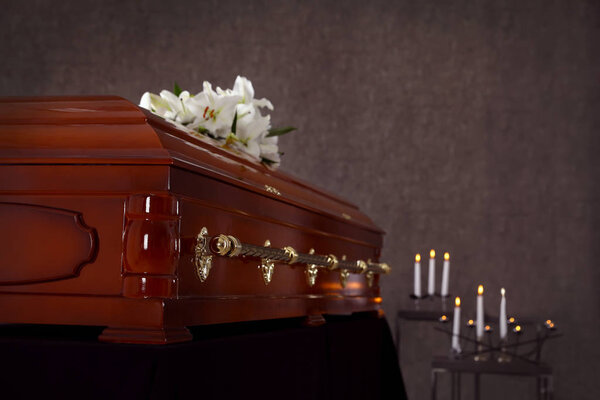 Wooden casket with white lilies in funeral home