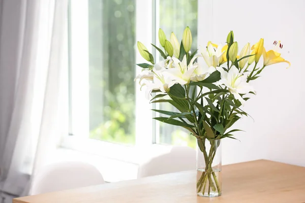 Florero con ramo de hermosos lirios en mesa de madera en el interior. Espacio para texto — Foto de Stock