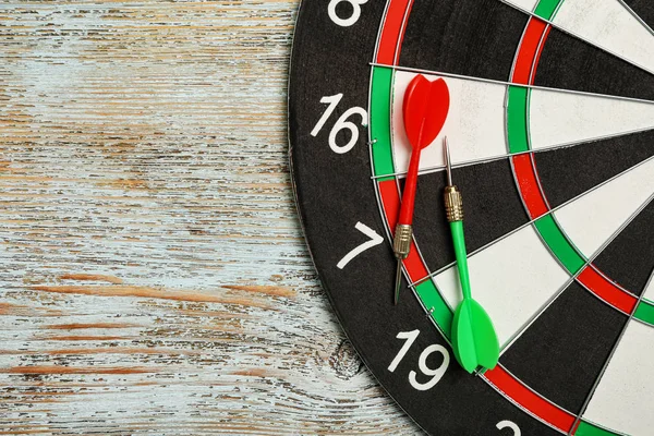Dart board with arrows on color wooden background, top view. Space for text — Stock Photo, Image