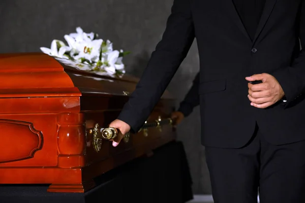 Jovem carregando caixão de madeira na funerária, close-up — Fotografia de Stock