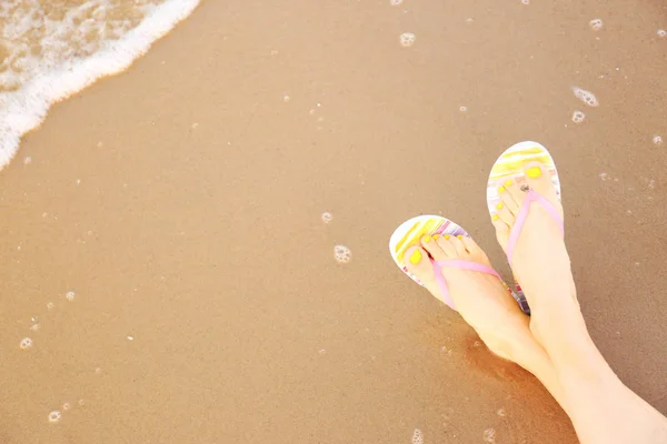 Close-up van de vrouw met stijlvolle flip flops op zand in de buurt van zee, ruimte voor tekst. Strand accessoires — Stockfoto