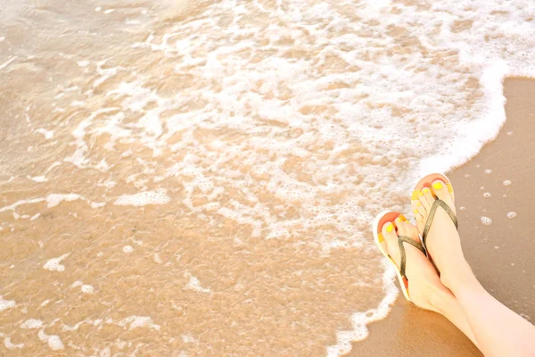 Close-up van de vrouw met stijlvolle flip flops op zand in de buurt van zee, ruimte voor tekst. Strand accessoires — Stockfoto