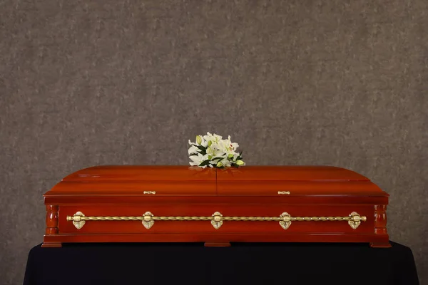 Trä begravning Kista med vita liljor på Grey Wall — Stockfoto