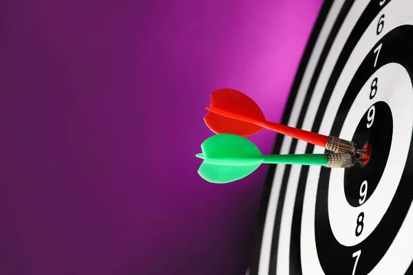 Arrows hitting target on dart board against purple background — Stock Photo, Image