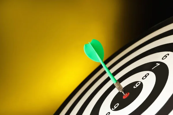 Flecha verde golpeando objetivo en tablero de dardos contra fondo amarillo. Espacio para texto —  Fotos de Stock