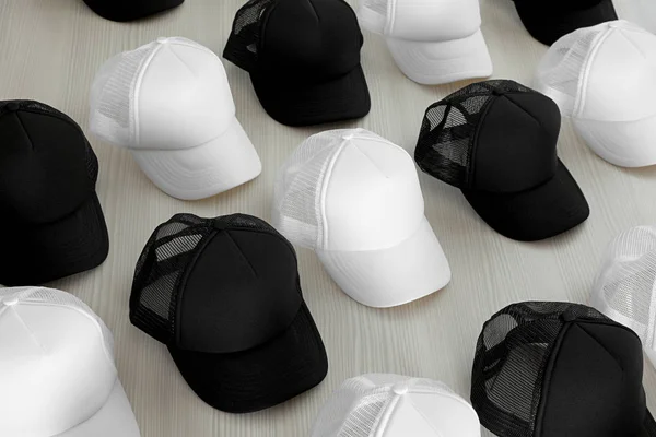 Nombreux chapeaux blancs et noirs vierges sur table en bois. Maquette pour le design — Photo
