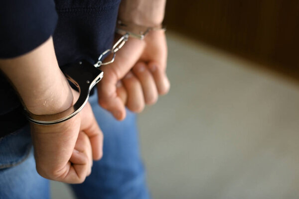 Мужчина, задержанный в наручниках в помещении, место для смс. Уголовное право
