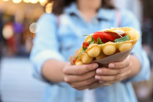 Młoda kobieta trzyma pyszne wafel bańka z pomidorów i rukolą na zewnątrz, zbliżenie — Zdjęcie stockowe