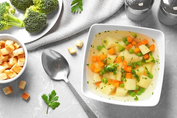 Bowl de supă proaspătă de legume de casă servită pe masă de marmură gri, așezată plat — Fotografie, imagine de stoc