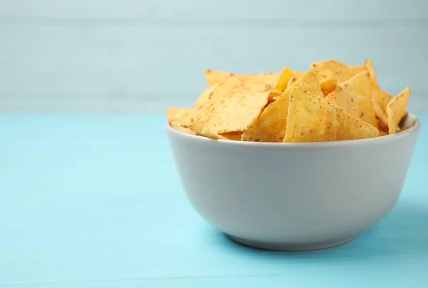 Bowl van smakelijke Mexicaanse nacho's chips op licht blauwe tafel — Stockfoto