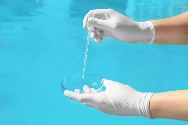 Femme goutte à goutte échantillon d'eau de piscine dans la boîte de Petri pour vérifier le niveau de PH à l'extérieur, gros plan — Photo