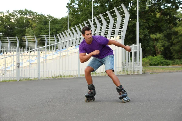 Handsome young man roller skating outdoors. Recreational activity