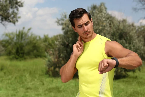 Un joven revisando el pulso después de entrenar en el parque. Espacio para texto — Foto de Stock