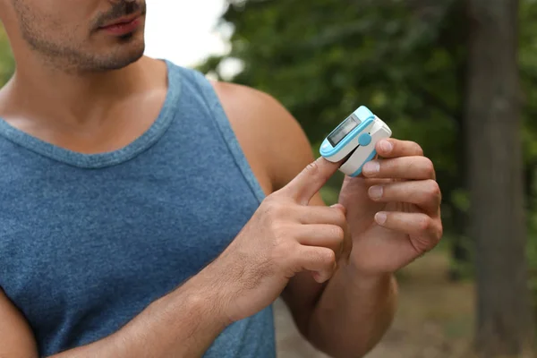 Giovane uomo che controlla il polso con dispositivo medico dopo l'allenamento nel parco, primo piano — Foto Stock