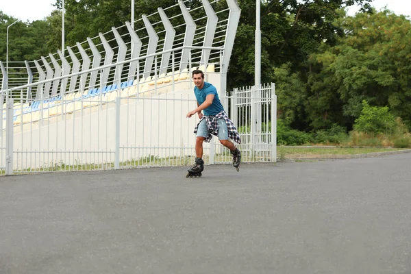 Handsome young man roller skating outdoors. Recreational activity