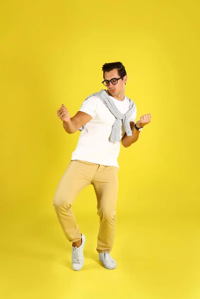 Handsome young man dancing on yellow background — Stock Photo, Image