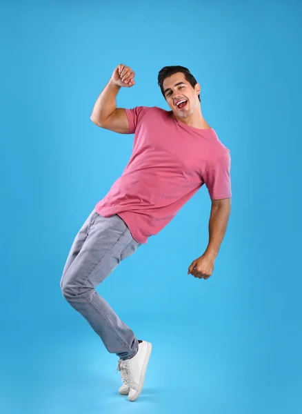 Красивый молодой человек танцует на синем фоне — стоковое фото