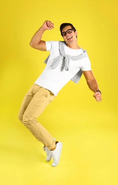 Красивый молодой человек танцует на жёлтом фоне — стоковое фото