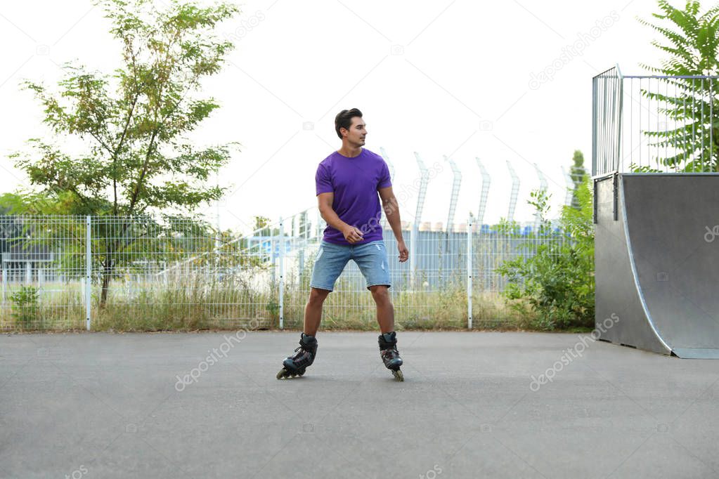 Handsome young man roller skating in park