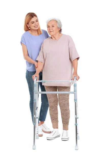 Επιστάτης βοηθώντας ηλικιωμένη γυναίκα με το βάδισμα πλαίσιο σε λευκό φόντο — Φωτογραφία Αρχείου