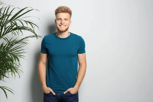 Young man wearing blank t-shirt on light background. Mockup for design — Stock Photo, Image