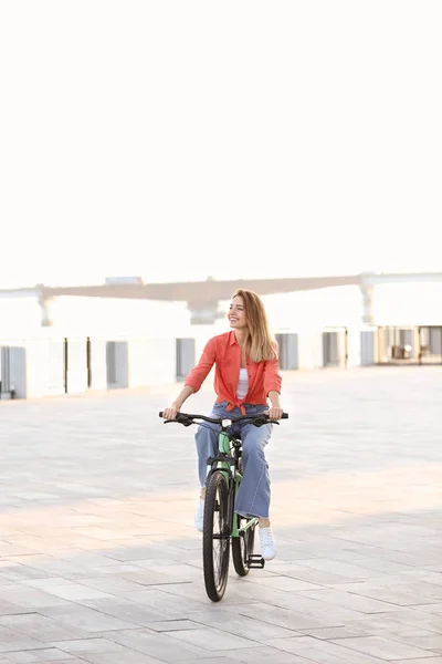 Молода жінка їде на велосипеді в місті в сонячний день — стокове фото