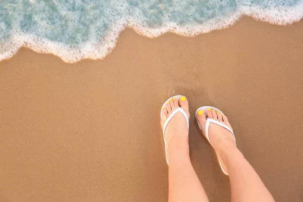 Vista dall'alto della donna con infradito bianche sulla sabbia vicino al mare, spazio per il testo. Accessori da spiaggia — Foto Stock