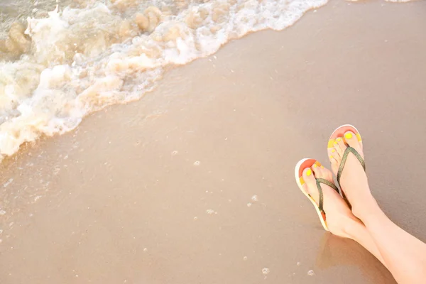 Närbild av kvinna med snygga flip flops på sand nära havet, utrymme för text. Strandtillbehör — Stockfoto