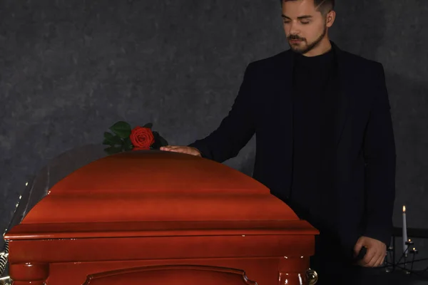 Junger Mann in der Nähe von Sarg mit roter Rose in Beerdigungsinstitut, Nahaufnahme — Stockfoto