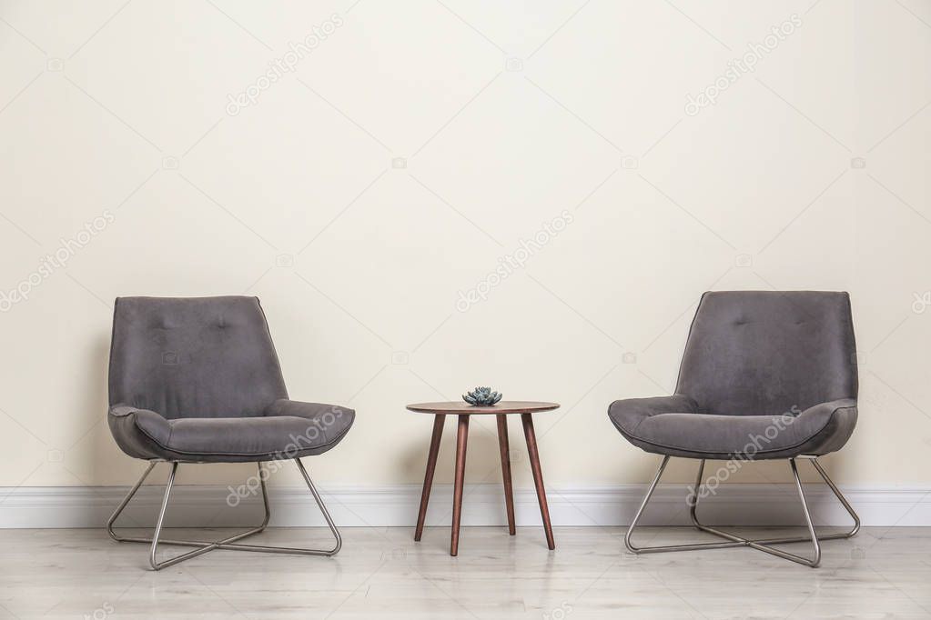Room interior with modern chairs and table near light wall