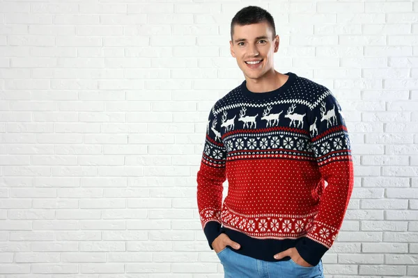 Retrato de jovem em camisola de Natal perto da parede de tijolo branco. Espaço para texto — Fotografia de Stock