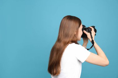 Açık mavi arka planda fotoğraf çeken profesyonel fotoğrafçı