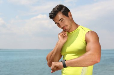 Young man checking pulse after training on beach. Space for text clipart