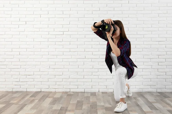Fotógrafo profissional tirando fotos perto da parede de tijolo branco. Espaço para texto — Fotografia de Stock