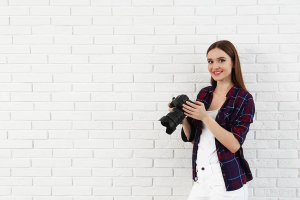 Fotógrafo profesional con cámara moderna cerca de la pared de ladrillo blanco. Espacio para texto —  Fotos de Stock