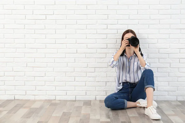 Fotógrafo profissional tirando fotos perto da parede de tijolo branco. Espaço para texto — Fotografia de Stock