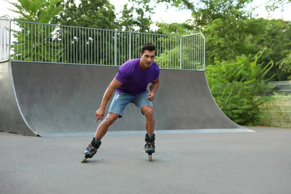 Guapo joven patinaje sobre ruedas en el parque — Foto de Stock