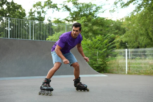 Guapo joven patinaje sobre ruedas en el parque — Foto de Stock