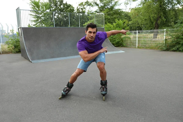 Guapo joven patinaje sobre ruedas en el parque — Foto de Stock